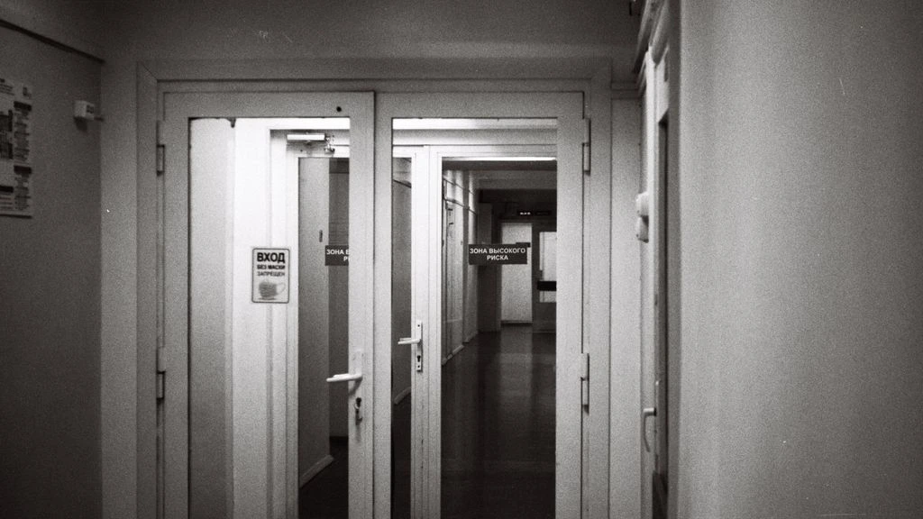 Documentary-style black-and-white photograph of a hospital corridor at dawn, used to set the tone of the Pfizer case study
